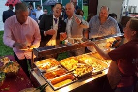 Wedding guests enjoying hog roast with baked potatoes
