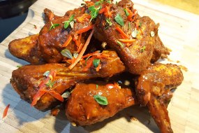 Slow smoked chicken wings tossed in hot sauce. Fresh thyme and chilli garnish