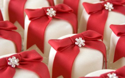 Mini cakes in white fondant with red bows and  brooches.