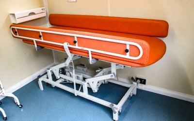 Electrically adjustable changing bench with safety rails.