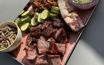 A tray of beef dino ribs, pulled pork, greek potato salad, green chilli slaw, and pickles.