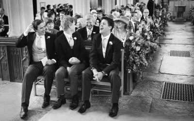 Groom and groomsmen laughing in church prior to wedding ceremony