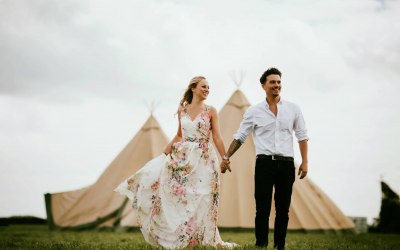 A couple walking from a two tipi set up, perfect for 100 guests.