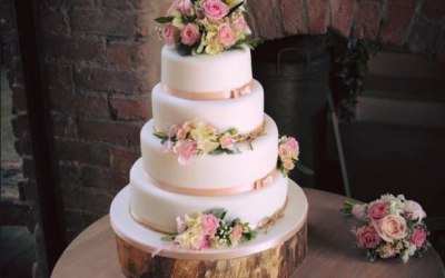 A Beautiful Four Tier weddig cake in a simple blush pink theme, decorated with fresh flowers, by The Daisy Chain Bakery