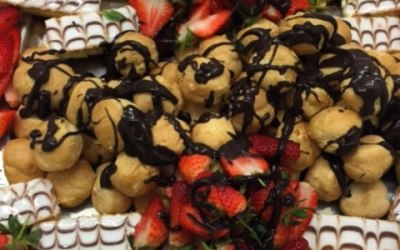 Profiteroles and strawberries with a chocolate drizzle, and cream slices.