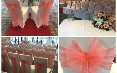 White chair covers and coral organza sashes