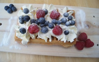 waffle with whipped cream, raspberries, blueberries and caster sugar topping