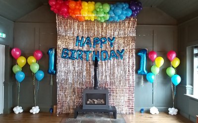Rainbow themed 1st birthday balloon display 