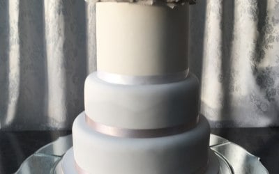 Sophisticated grey and white cake featuring silk grey roses and white hydrangea