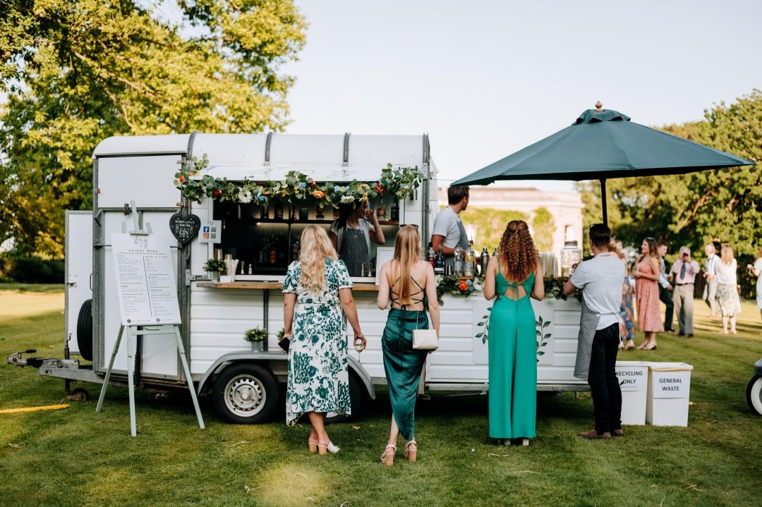A couple chatting to each other whilst standing outside a parked horsebox food van