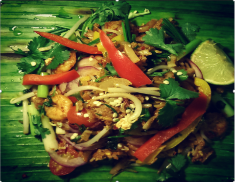 Spicy Prawns - Flat Rice noodles lightly chilli spiced with Spicy Prawns, beansprouts, Peppers and spring onions which is freshly wrapped and roasted in Banana Leaf (Vegetarian option available)
