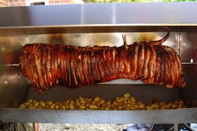 Whole Hog Roast on the spit with baby roasted potatoes, rosemary and garlic. Spit and Grill BBQ Company