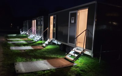 A set of matching toilet trailers for a larger event, with led lighting inside and on the steps.