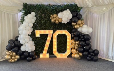 4ft white light up number 70 with balloons and a foilage backdrop