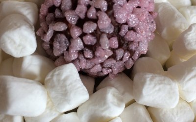 Champagne truffle coated in strawberry sugar on a bed of mini marshmallows