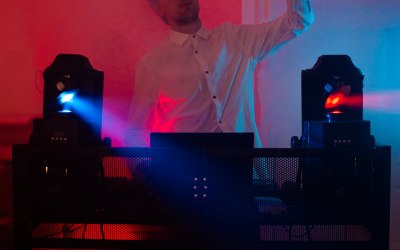 DJ dancing over his decks with colourful lights,