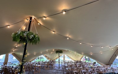 'Ingleborough' 16x31m stretch tent, with walls and windows, set up with rustic furniture, lights and floristry hoop for festival style wedding 