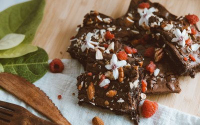 Chocolate brownies topped with coconut flakes, edible flowers, nuts & raspberries.