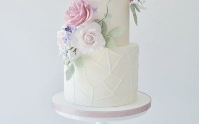 ✨ Modern Romance ✨ A timeless design with a contemporary twist. Three tiers of smooth fondant, adorned with delicate handcrafted sugar flowers and a textured geometric base for a touch of modern artistry. 