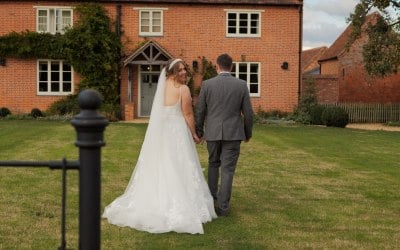 Bride and Groom walk towards country home