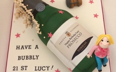 A handcarved Prosecco bottle shaped birthday cake with edible printed label and handmade model of th ebirthday girl!