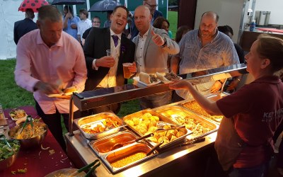 Wedding guests enjoying hog roast with baked potatoes