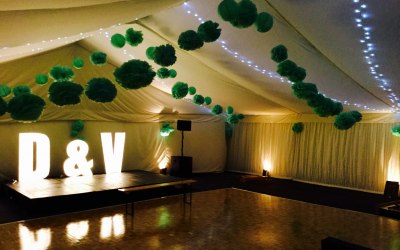 Illuminated letters and uplighter in a summer marquee