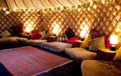 A cosy yurt with cushions, warm lighting and rugs.