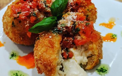 Crab Arancini stuffed with mozzarella and topped with tomato and chilli salsa, fresh basil oil and grated parmesan