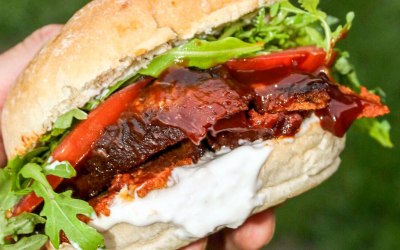 Our Brizket Burg, smoked BBQ seitan brisket with rocket, chargrilled tomatoes, and mayo, in a floury bap.
