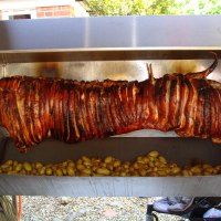 Whole Hog Roast on the spit with baby roasted potatoes, rosemary and garlic. Spit and Grill BBQ Company