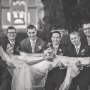 black and white bride laying across groomsmen