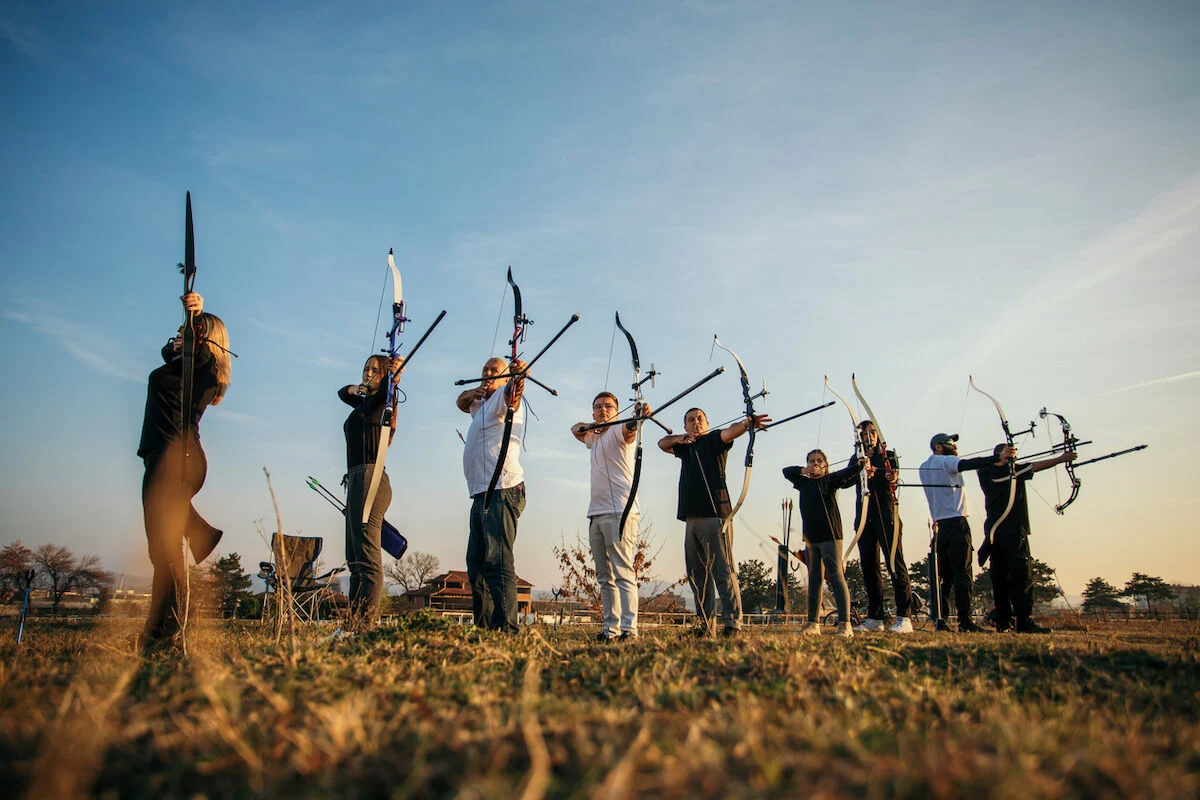 A group of people lined up enjoying a mobile archery session