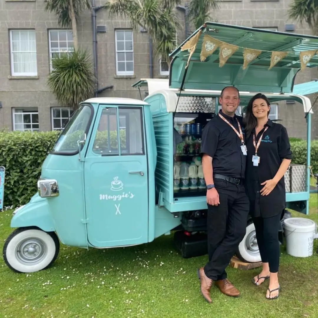 Maggie’s Mobile Barista owners in front of their converted coffee bar at an outdoor event