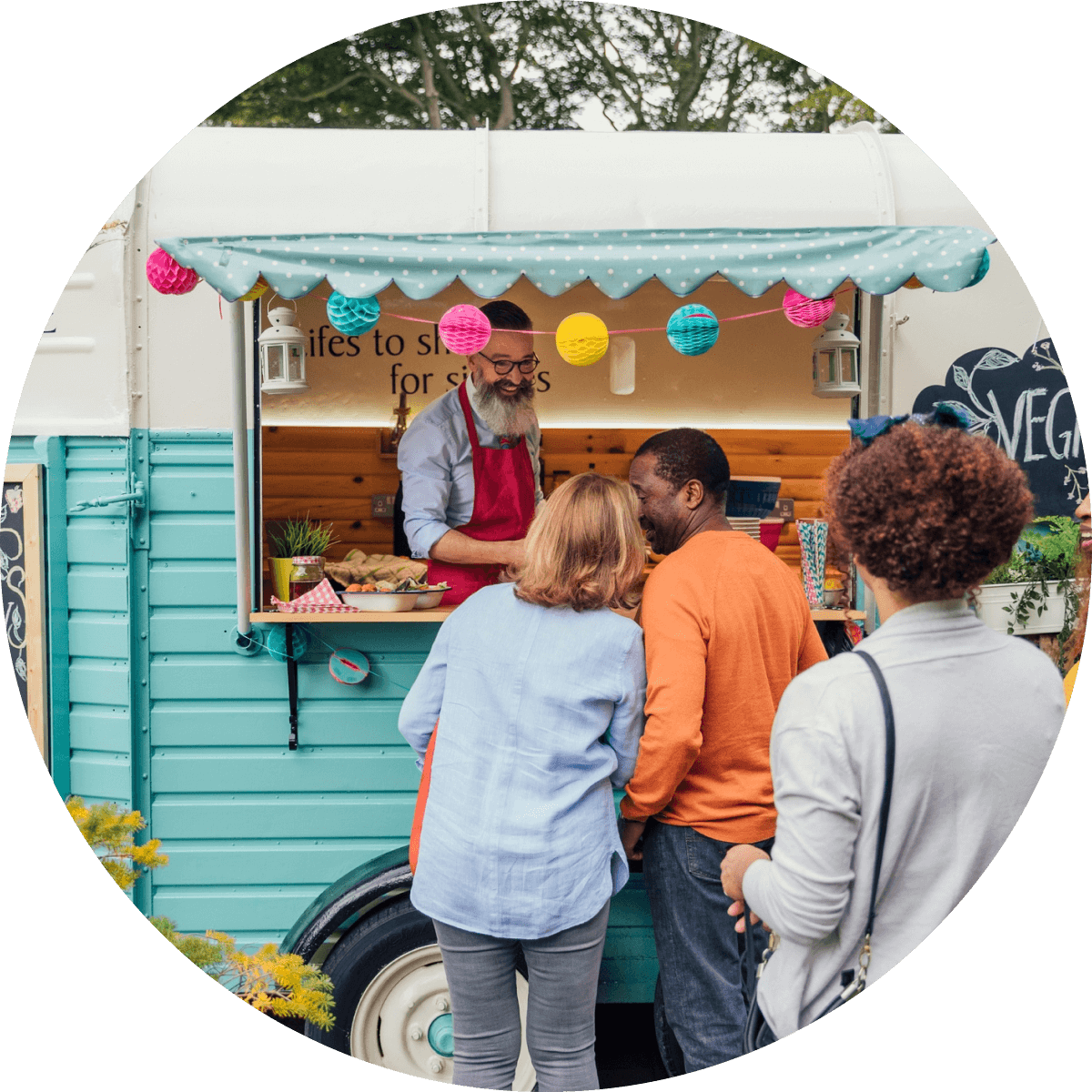 A couple chatting to each other whilst standing outside a parked horsebox food van