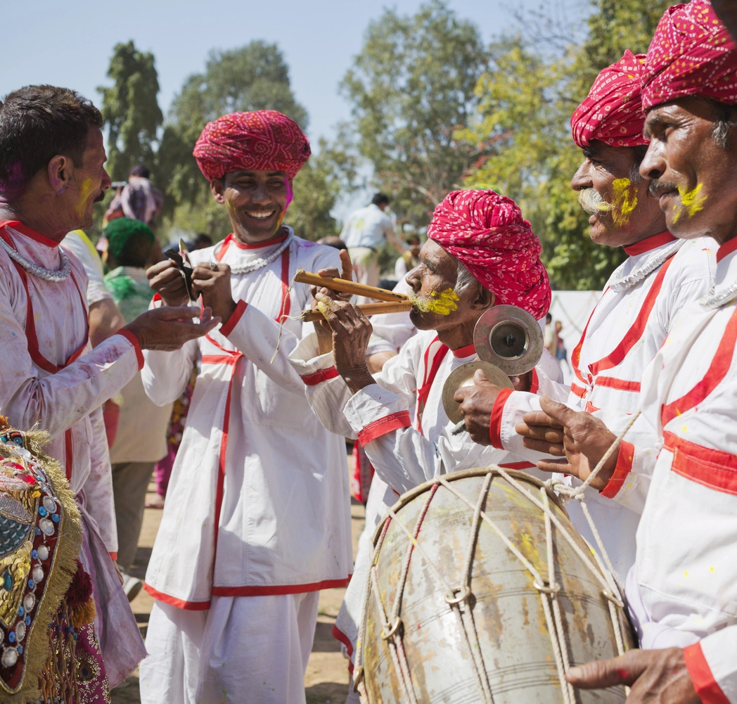 A group of indian men performing music outside on a sunny day