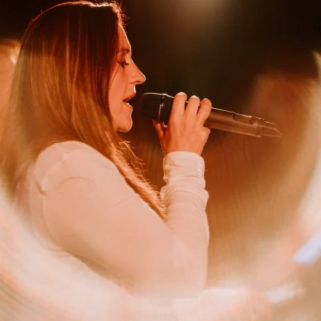 Image of a female singer performing and singing into a microphone