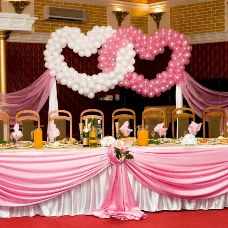 Image of the bride and grooms decorated table with a heart-shaped arrangement of balloons behind