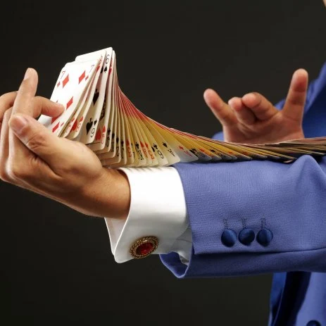 Up close image of a magician performing a card trick with a deck of cards