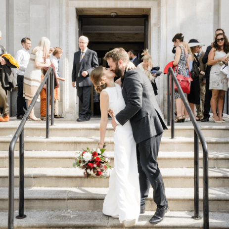 Image of a bride and groom passionately kissing in front of the church
