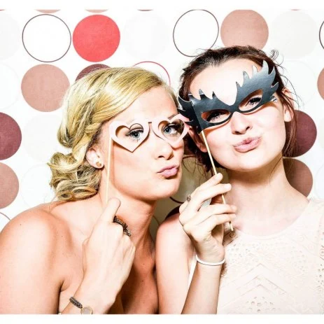 Image of two women using props and posing for the photo booth