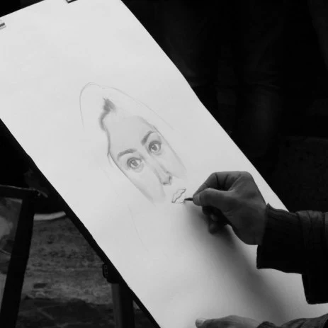 Black and white image of a caricaturist drawing a persons face