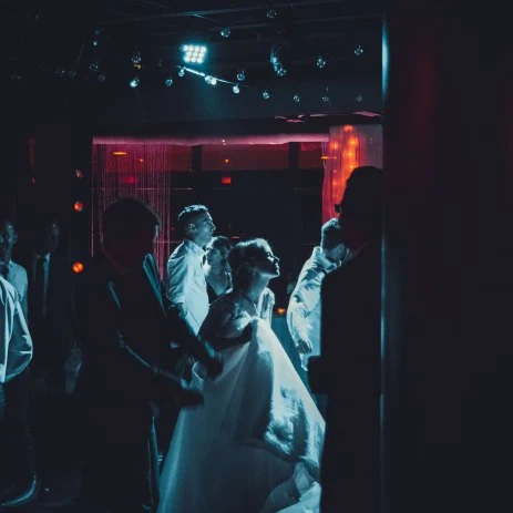Image of a dark dance floor with the bride and groom dancing in front of the DJ