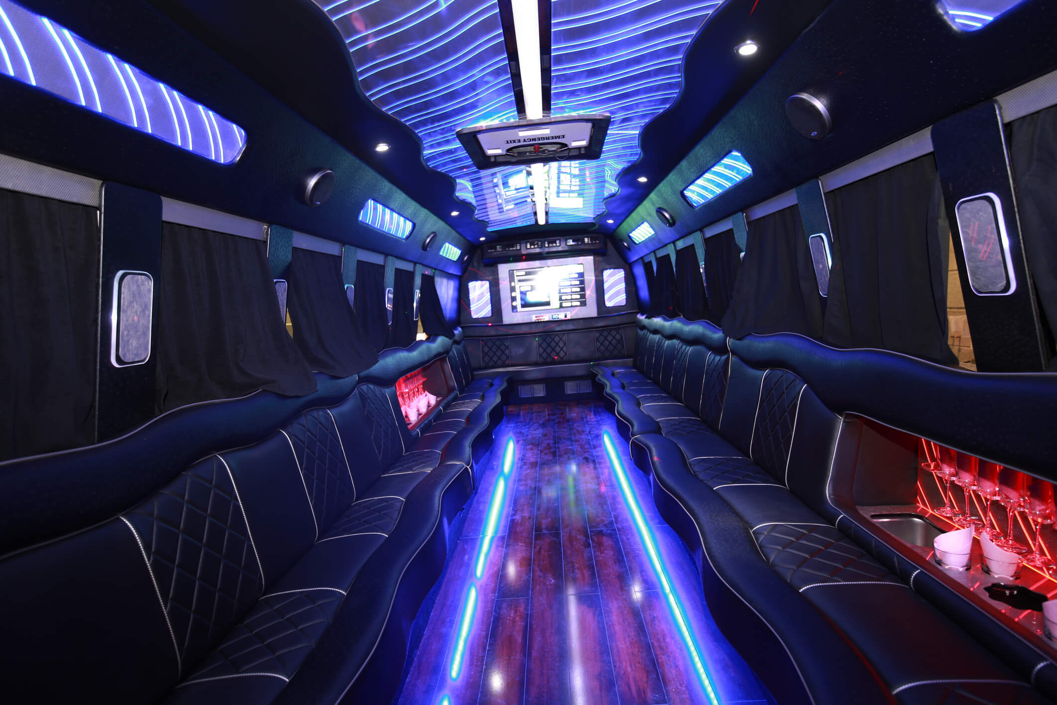 Interior of party bus with black leather seats and blue trim lighting