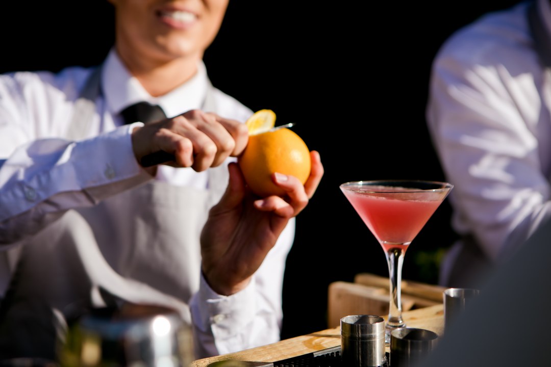 Bartender slicing orange peel to add to the cocktail