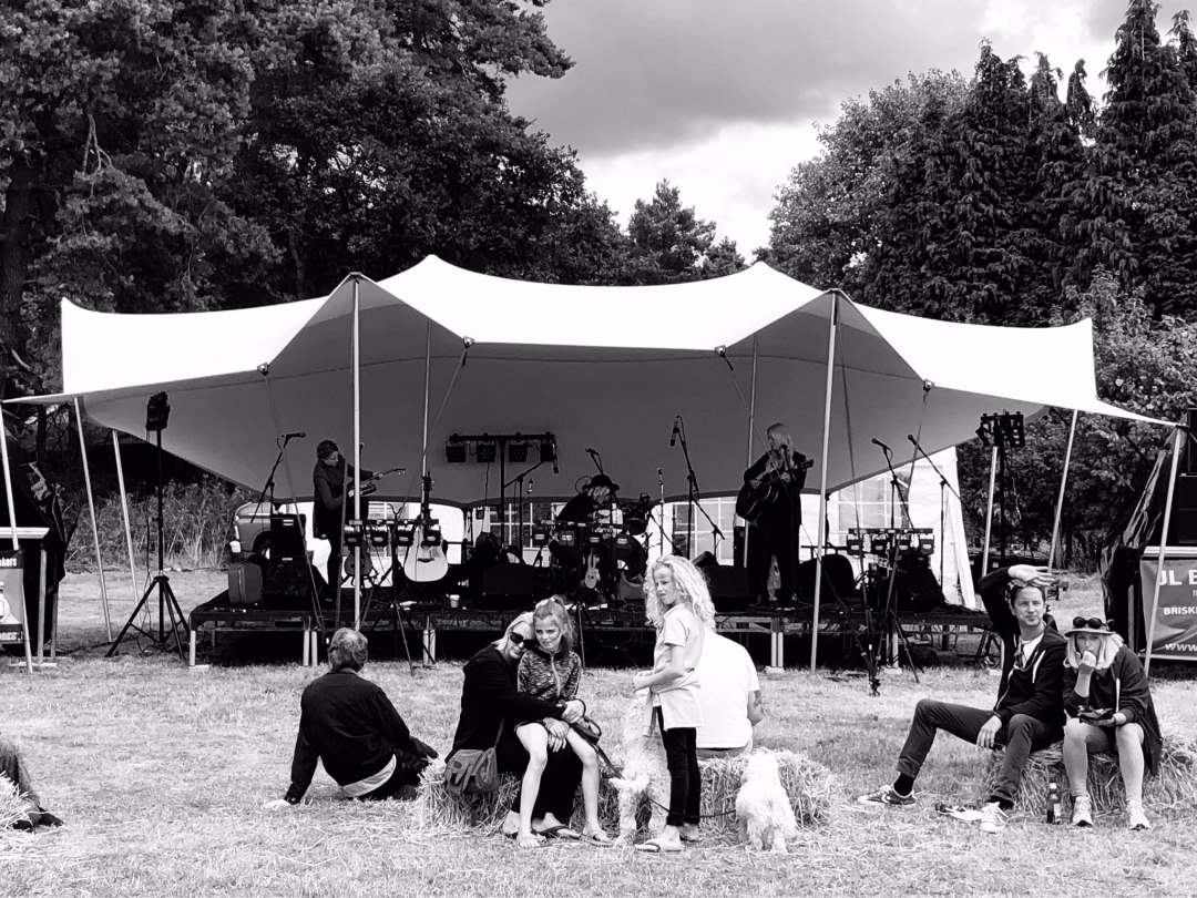 Pop up marquee tent protecting musical stage at outdoor event