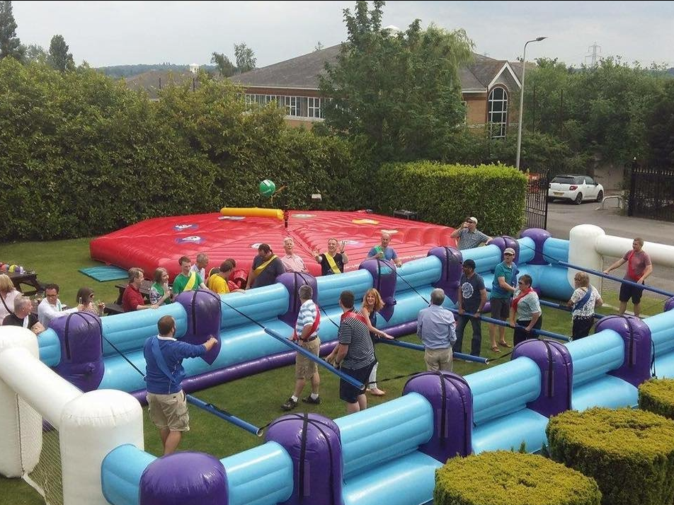 Inflatable life size table football being enjoyed at an outdoor event