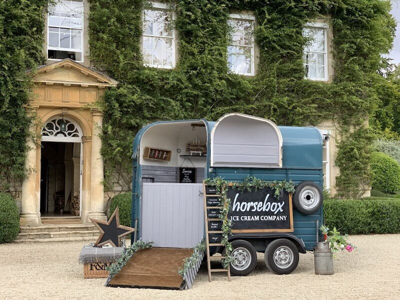 Vintage horsebox ice cream van in front of large house