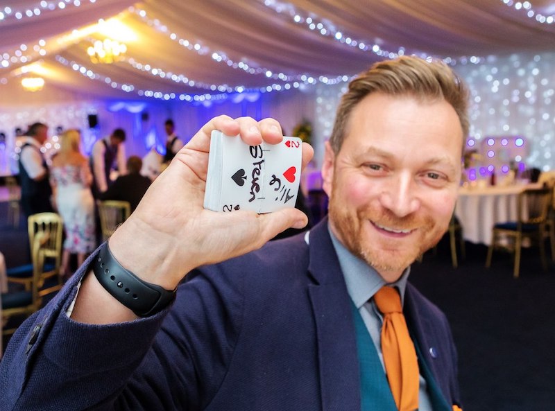 Steve Rowe - The lovable trickster holding pack of cards at a wedding