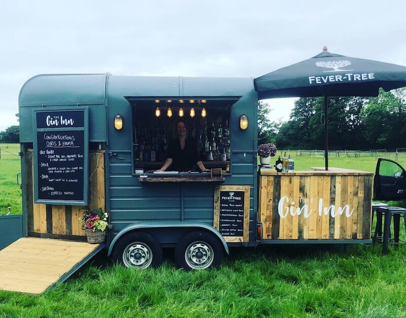 The dark green Gin Inn horsebox bar set up at an outdoor event